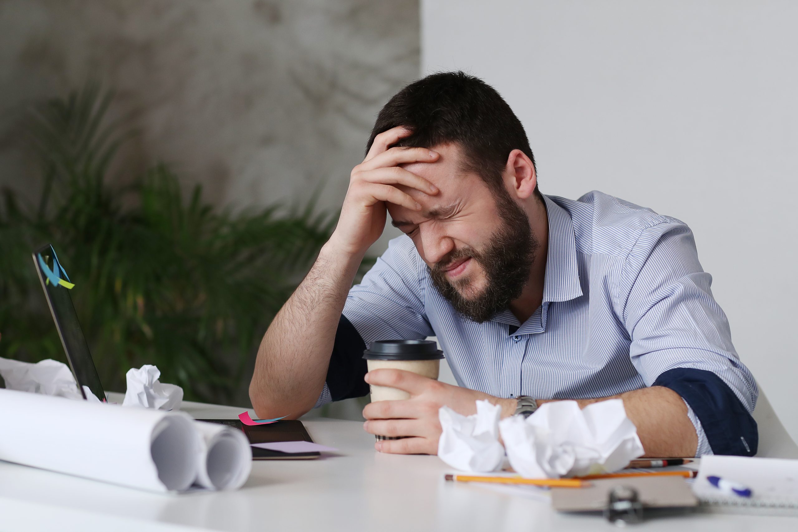 Hombre trabajando en la oficina con dolor de cabeza