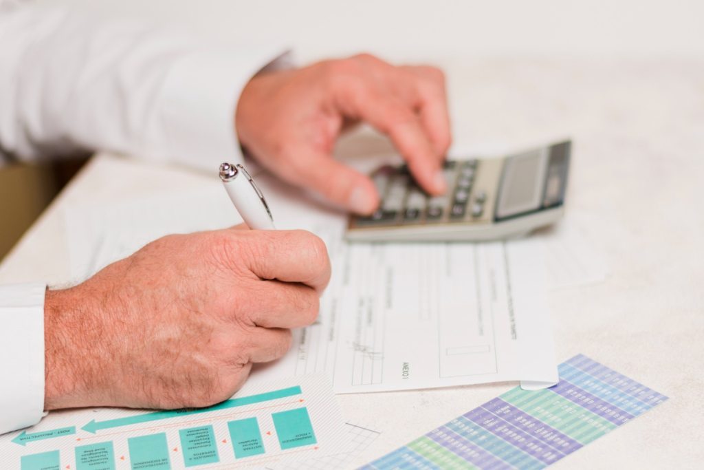 Hombre de negocios realizando cuentas de su empresa con una calculadora